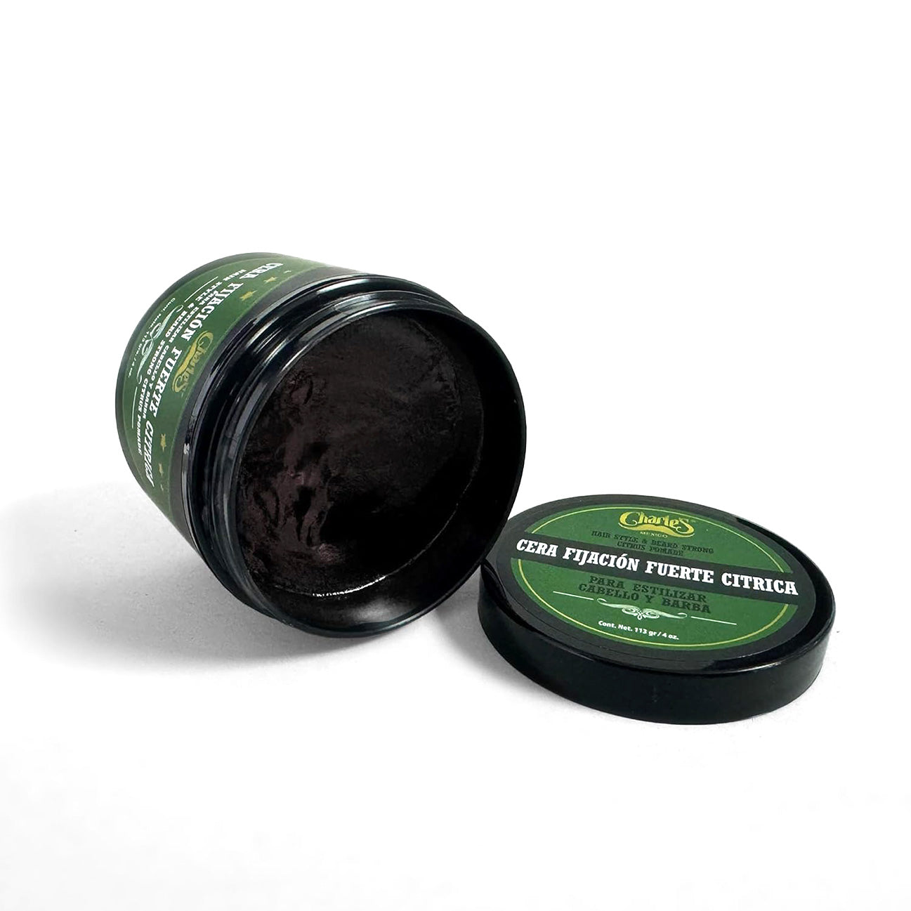 Open jar of black wax with green lid and label on a white background