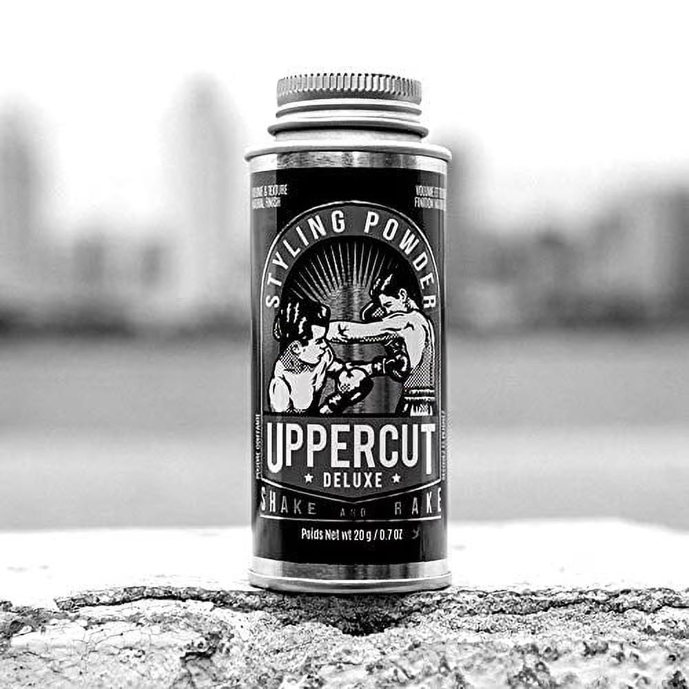 Uppercut Deluxe Styling Powder canister on a textured surface with a blurred background. Uppercut Styling Powder black and white – premium men's hair styling product, natural finish