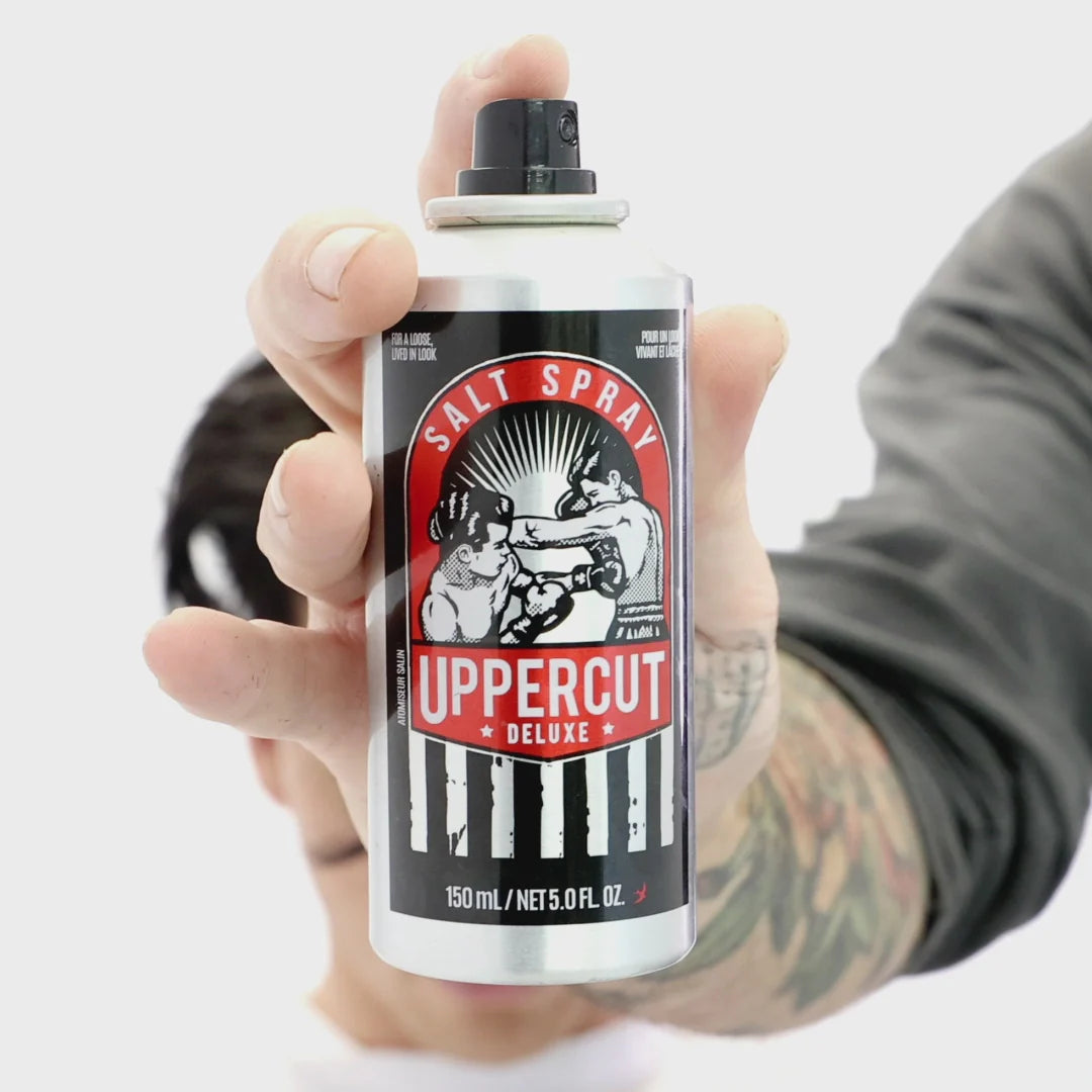 Uppercut Salt Spray non-aerosol pump bottle held in hand – 150ml men's hair texturizing spray. Hand holding a can of Uppercut Deluxe Salt Spray against a white background